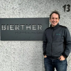 Der Geschäftsführer der Bierther GmbH posiert lächelnd vor dem Firmenschild.