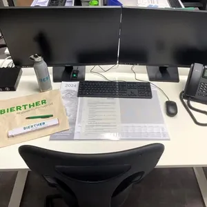 Neuer Büro-Arbeitsplatz mit 2 Bildschirmen, Tastatur, Telefon und Willkommensgeschenk.
